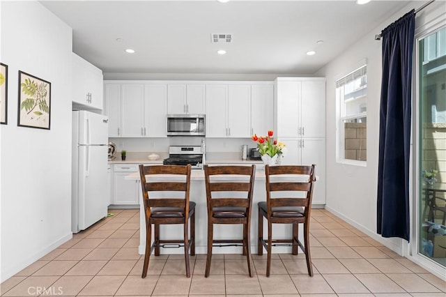 kitchen featuring light countertops, visible vents, white cabinetry, appliances with stainless steel finishes, and a breakfast bar area