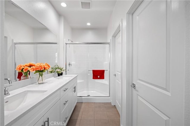full bathroom featuring tile patterned flooring, visible vents, a sink, and a shower stall