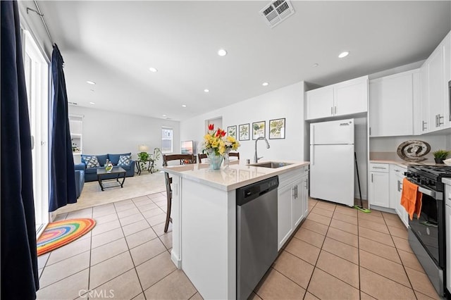 kitchen featuring visible vents, stainless steel dishwasher, a sink, freestanding refrigerator, and black gas range
