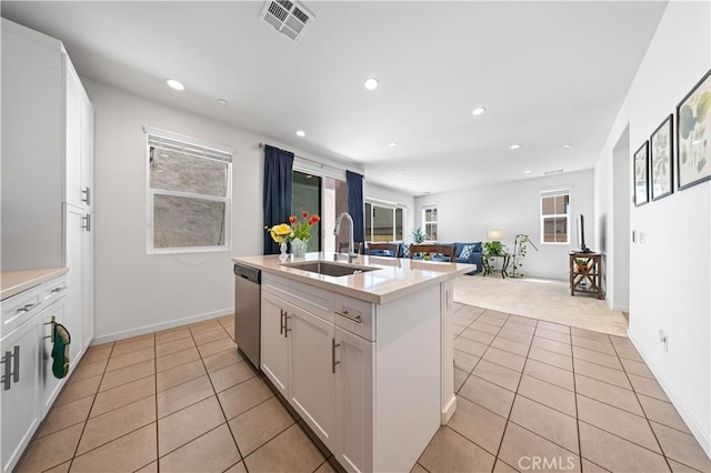 kitchen featuring visible vents, stainless steel dishwasher, a sink, light tile patterned flooring, and open floor plan