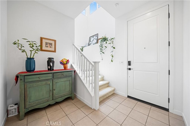 entryway with stairway, baseboards, and light tile patterned floors