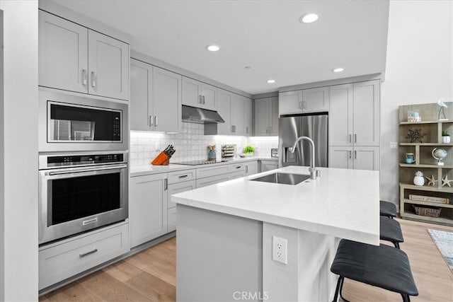 2902 Foundry Ct, Redondo Beach, CA 90278 - kitchen with a kitchen breakfast bar, under cabinet range hood, a sink, backsplash, and stainless steel appliances