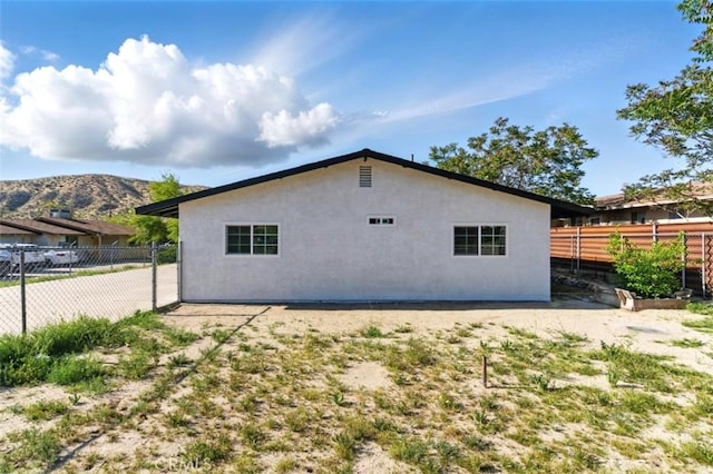 49537 Rosella Dr, Morongo Valley, CA 92256 - view of home's exterior with a mountain view, stucco siding, and fence