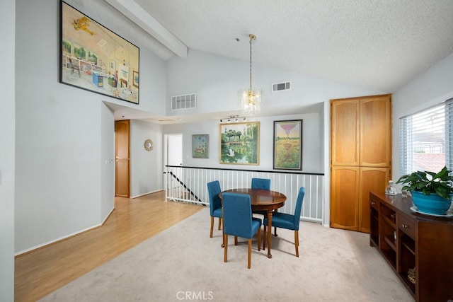 dining space with vaulted ceiling, a chandelier, light wood-type flooring, and a textured ceiling