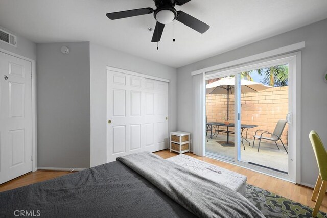 bedroom with access to outside, wood finished floors, ceiling fan, and a closet