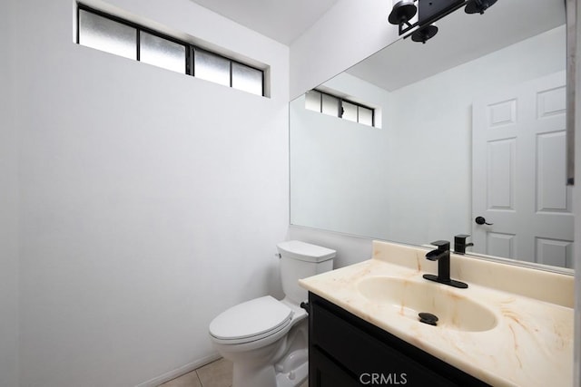 half bathroom with plenty of natural light, vanity, toilet, and tile patterned flooring