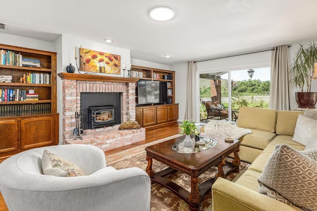living area with visible vents, wood finished floors, recessed lighting, and a wood stove