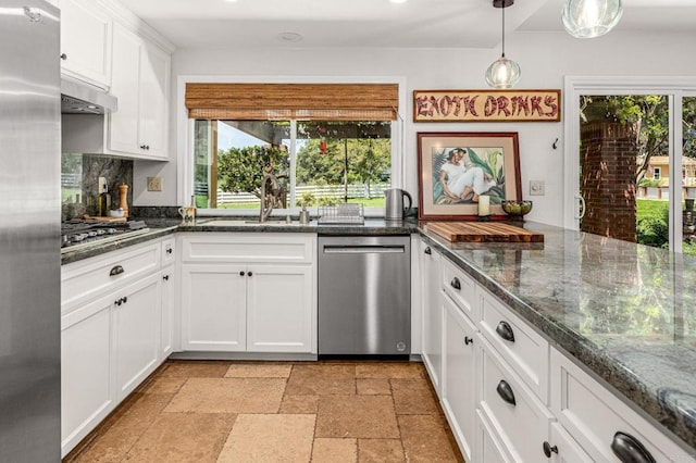 kitchen with a sink, stone tile floors, stainless steel appliances, white cabinets, and under cabinet range hood