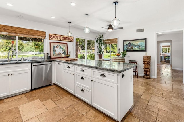 kitchen with recessed lighting, white cabinets, stainless steel dishwasher, a sink, and stone tile flooring