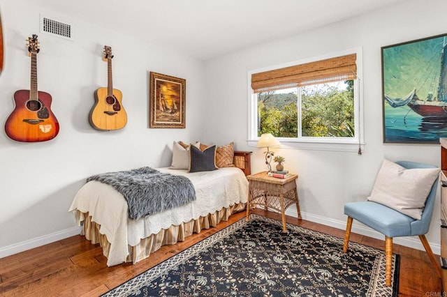 bedroom featuring wood finished floors, visible vents, and baseboards