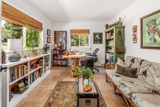 office space with radiator, plenty of natural light, and stone tile floors