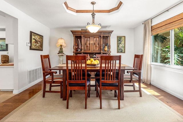 dining space with baseboards, visible vents, light wood-style floors, and a tray ceiling