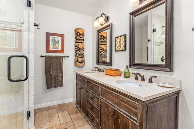 bathroom with stone tile flooring, a sink, and a stall shower