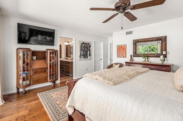 bedroom featuring baseboards, visible vents, wood finished floors, ceiling fan, and connected bathroom