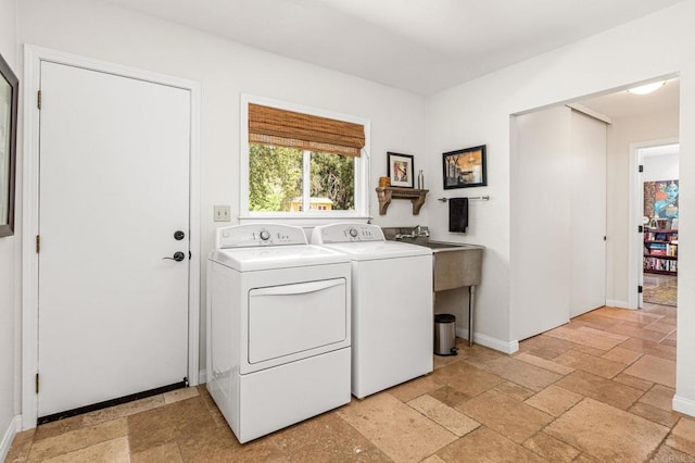 laundry room featuring separate washer and dryer, baseboards, stone tile flooring, and laundry area
