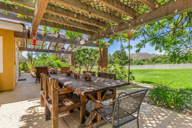 view of patio featuring a pergola, outdoor dining area, fence, and a mountain view
