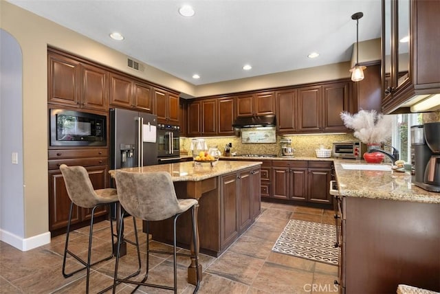 9 Healdsbury, Irvine, CA 92602 - kitchen featuring a breakfast bar area, stainless steel appliances, under cabinet range hood, visible vents, and a kitchen island