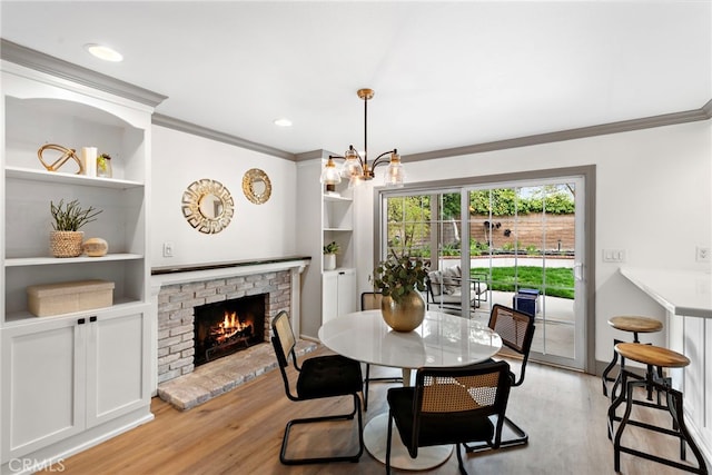 28166 Camellia Ct, Laguna Niguel, CA 92677 - dining room featuring a chandelier, built in features, a fireplace, light wood finished floors, and crown molding