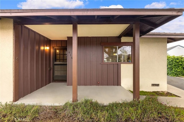view of exterior entry with a patio and stucco siding