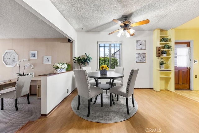 dining area with light wood-style flooring, a textured ceiling, a ceiling fan, and baseboards