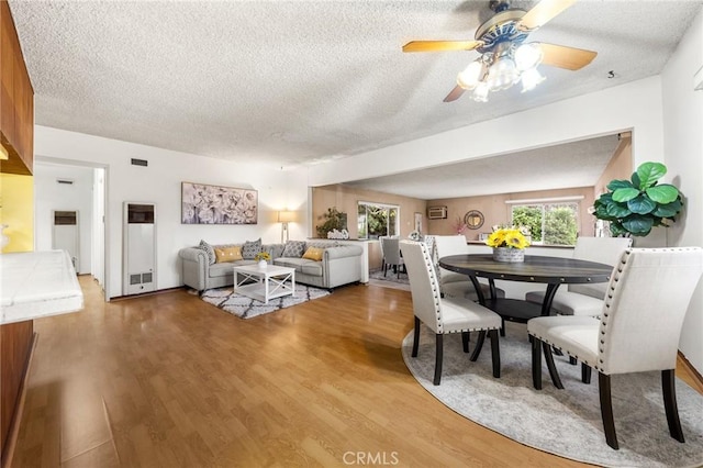 dining area with wood finished floors, a textured ceiling, and ceiling fan
