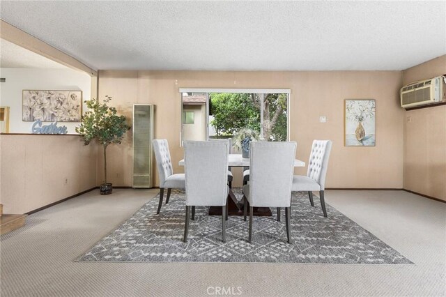 carpeted dining area with a wall mounted air conditioner, a textured ceiling, and baseboards