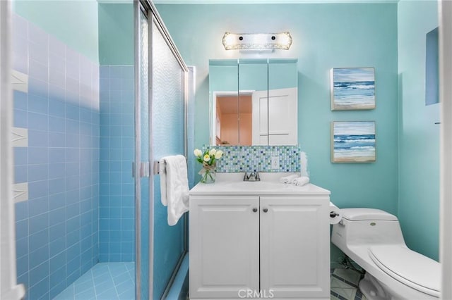bathroom featuring tasteful backsplash, vanity, toilet, and a stall shower