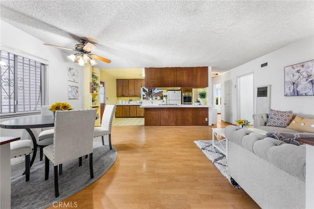 dining room featuring light wood-style flooring, a textured ceiling, and ceiling fan
