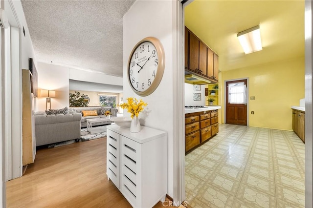 kitchen featuring a textured ceiling, brown cabinets, open floor plan, light floors, and light countertops
