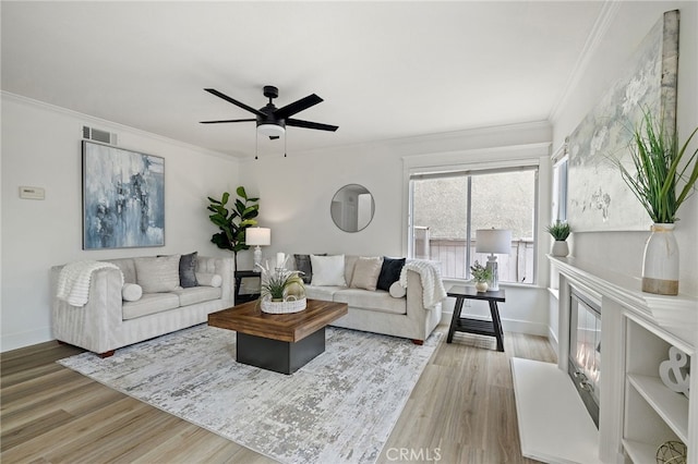 living area featuring visible vents, wood finished floors, a ceiling fan, and crown molding