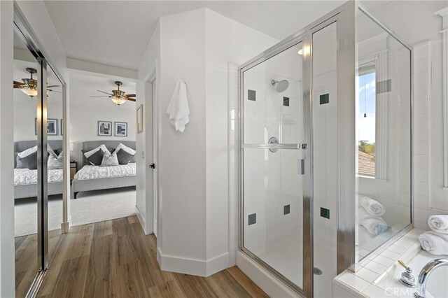 ensuite bathroom with wood finished floors, a shower stall, ensuite bath, and ceiling fan