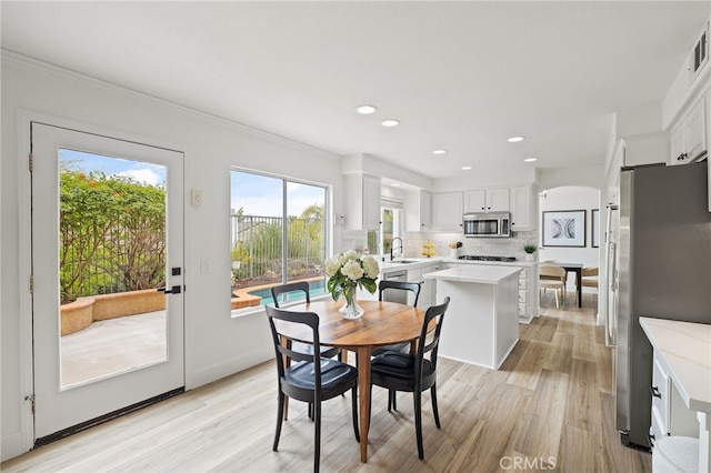 dining room featuring visible vents, light wood-type flooring, crown molding, and recessed lighting