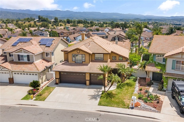 view of front facade featuring a garage, a mountain view, a residential view, and concrete driveway