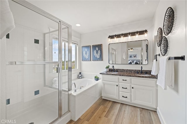bathroom featuring wood finished floors, a shower stall, a bath, and a sink