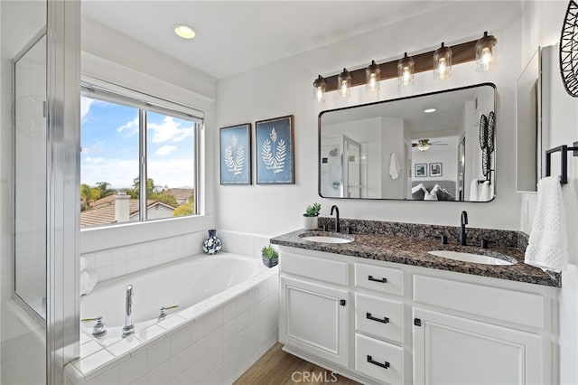 bathroom featuring a stall shower, a garden tub, double vanity, and a sink