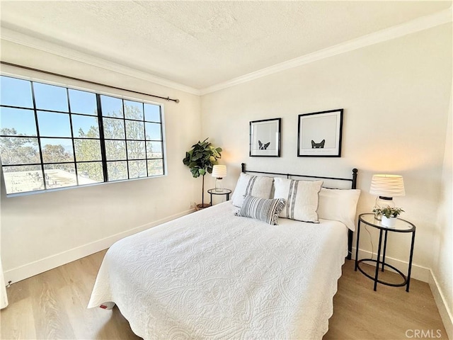 bedroom featuring wood finished floors, baseboards, ornamental molding, and a textured ceiling