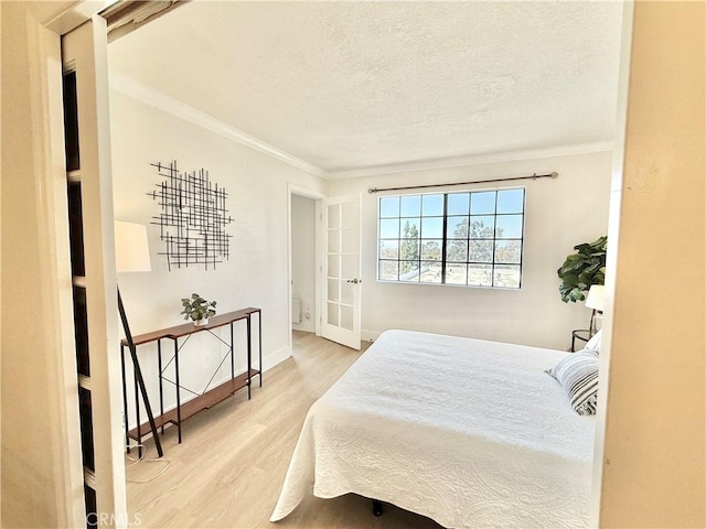 bedroom featuring wood finished floors, a textured ceiling, crown molding, baseboards, and french doors