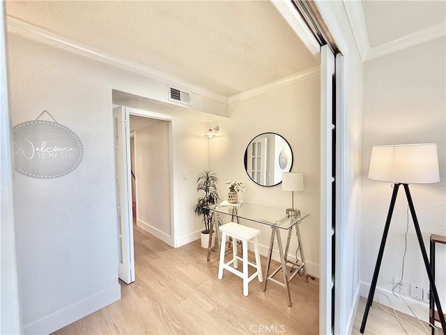 hallway with ornamental molding, light wood-style flooring, and baseboards