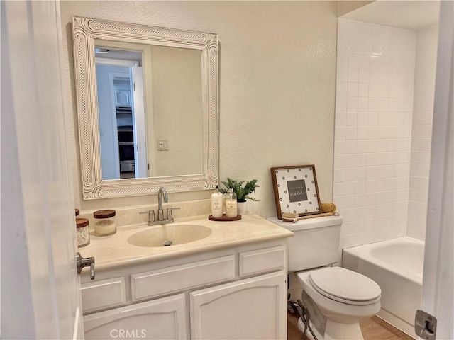 bathroom with toilet, vanity, and a textured wall