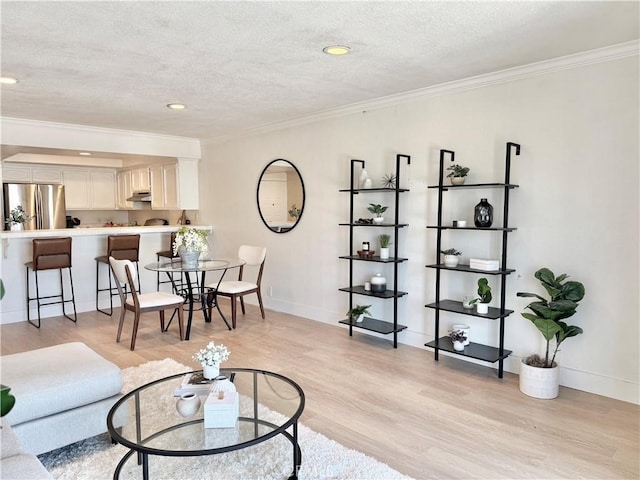 living area with ornamental molding, light wood-style floors, baseboards, a textured ceiling, and recessed lighting