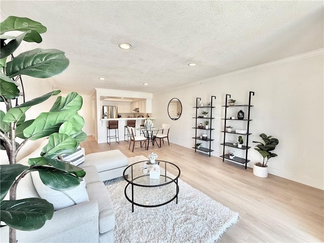 living area featuring light wood-style flooring, crown molding, a textured ceiling, recessed lighting, and baseboards