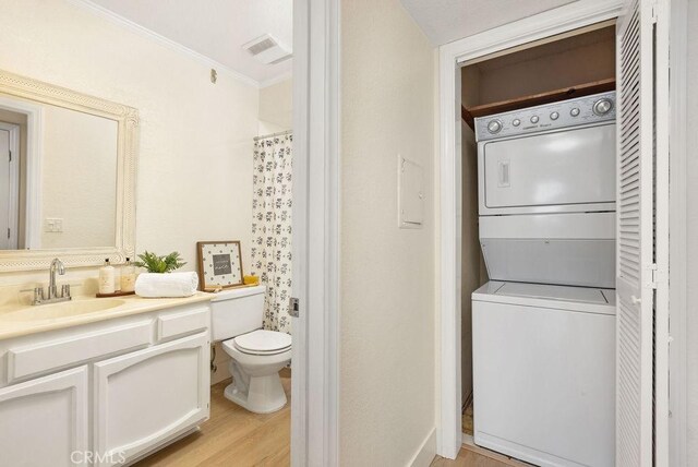 2599 Walnut Ave, Unit Signal Hill, CA 90755 - bathroom with stacked washing machine and dryer, toilet, ornamental molding, wood finished floors, and vanity