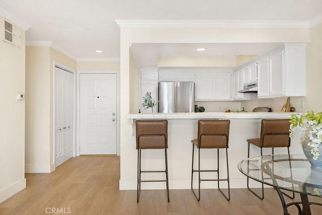 2599 Walnut Ave, Unit Signal Hill, CA 90755 - kitchen featuring freestanding refrigerator, under cabinet range hood, a peninsula, white cabinets, and light wood-style flooring