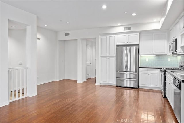 3240 S Westmont Ln Unit 5, Ontario, CA 91761 - kitchen featuring decorative backsplash, visible vents, white cabinets, appliances with stainless steel finishes, and wood finished floors