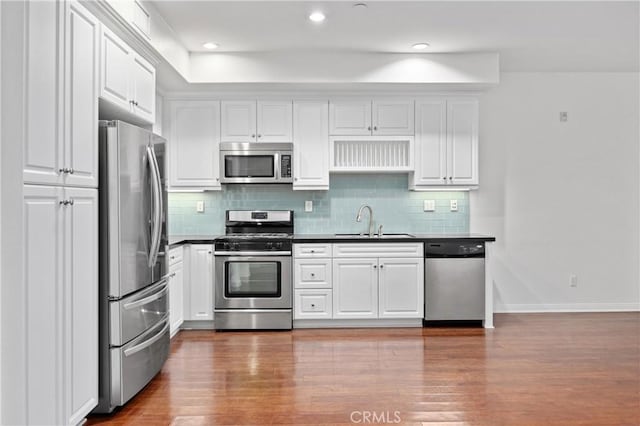3240 S Westmont Ln Unit 5, Ontario, CA 91761 - kitchen with stainless steel appliances, dark countertops, white cabinetry, backsplash, and wood finished floors