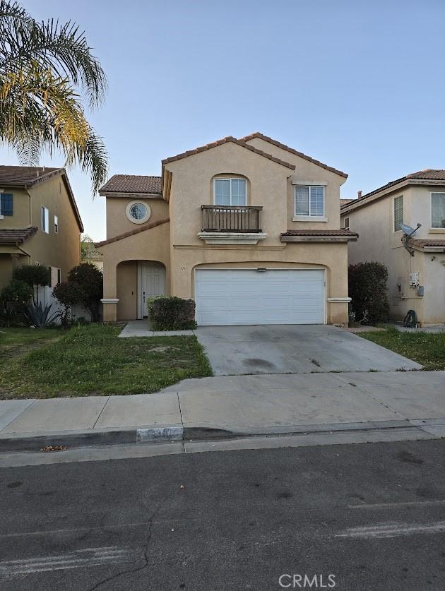 view of front of home with a balcony, stucco siding, an attached garage, a tile roof, and driveway