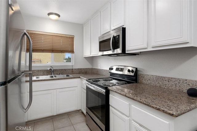 kitchen featuring a sink, light tile patterned floors, stainless steel appliances, white cabinets, and light stone countertops