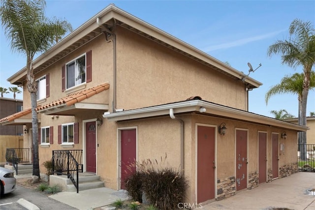townhome / multi-family property featuring stone siding, stucco siding, and fence