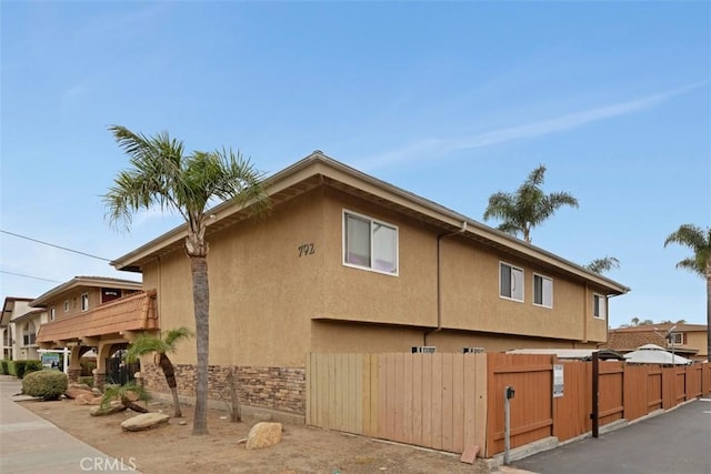 view of side of home with a gate, stucco siding, and fence