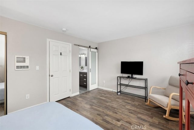 bedroom featuring a barn door, baseboards, and wood finished floors